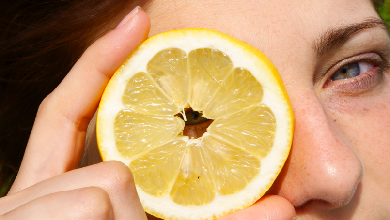 Woman looking through lemon slice.